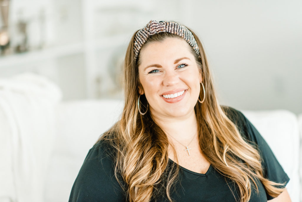 woman in black dress and headband smiles at camera for wedding planner headshots