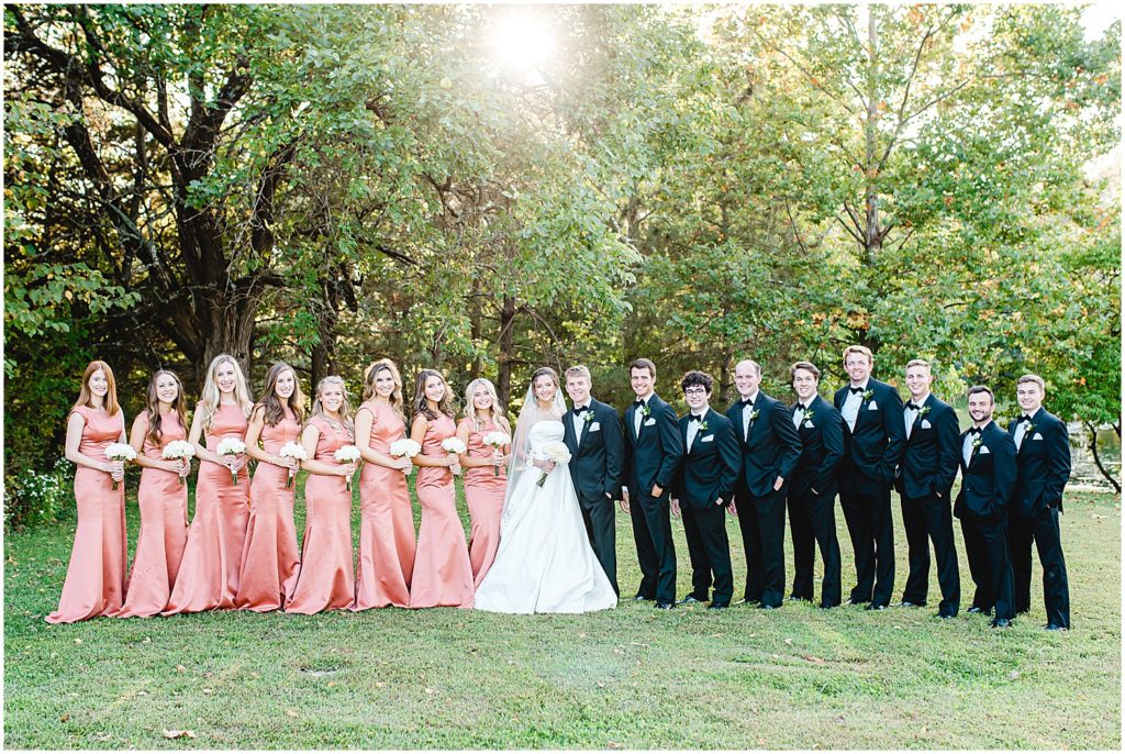 full wedding party portrait men in tuxes bridesmaids in rust colored satin dresses