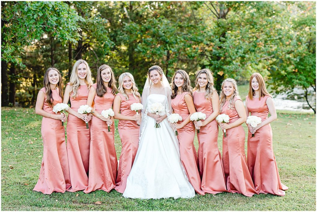 bride and bridesmaids in rust colored satin dresses smiling during portraits on wedding day