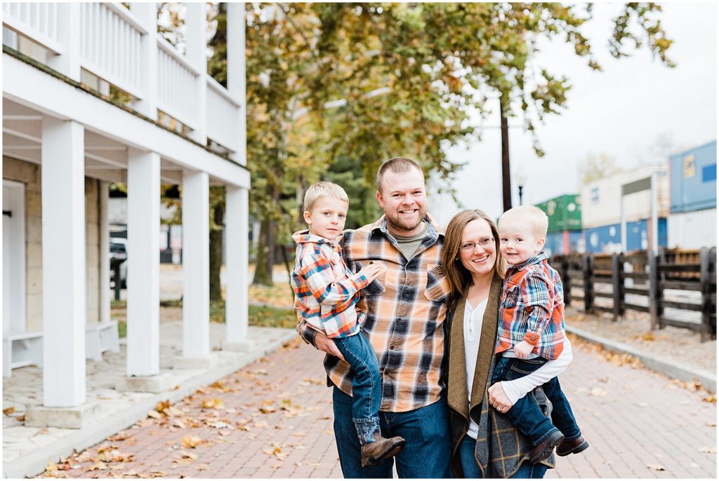 a young family with sons all wearing plaid with fallen leaves in the background