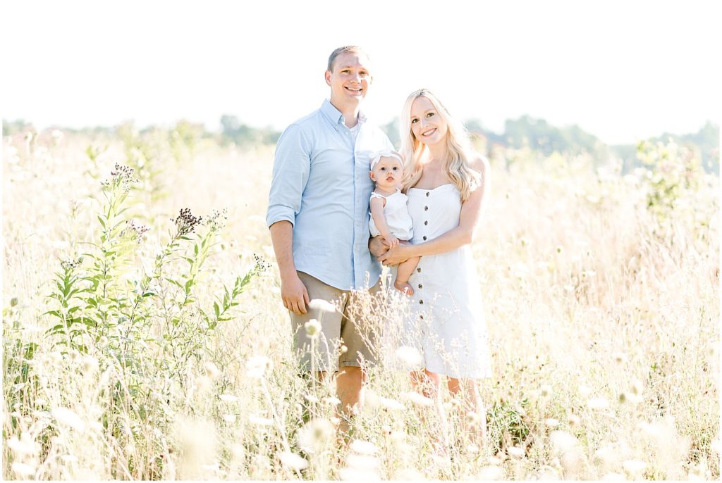 young couple holding baby in a field family portrait session