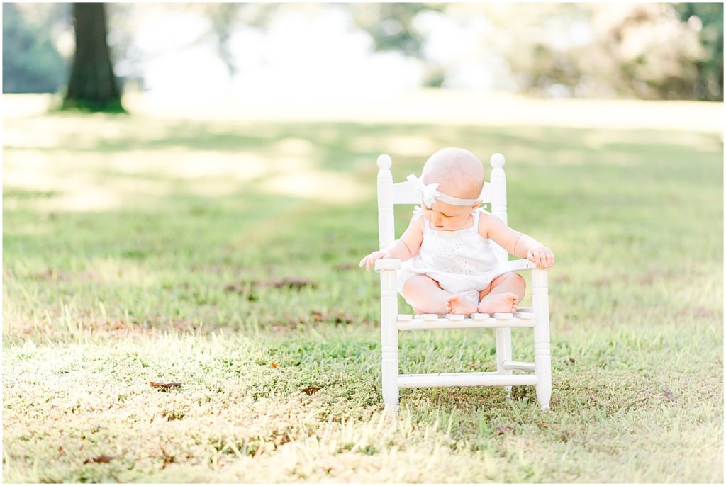 6 month old girl sitting in rocking chair in grass family portrait session