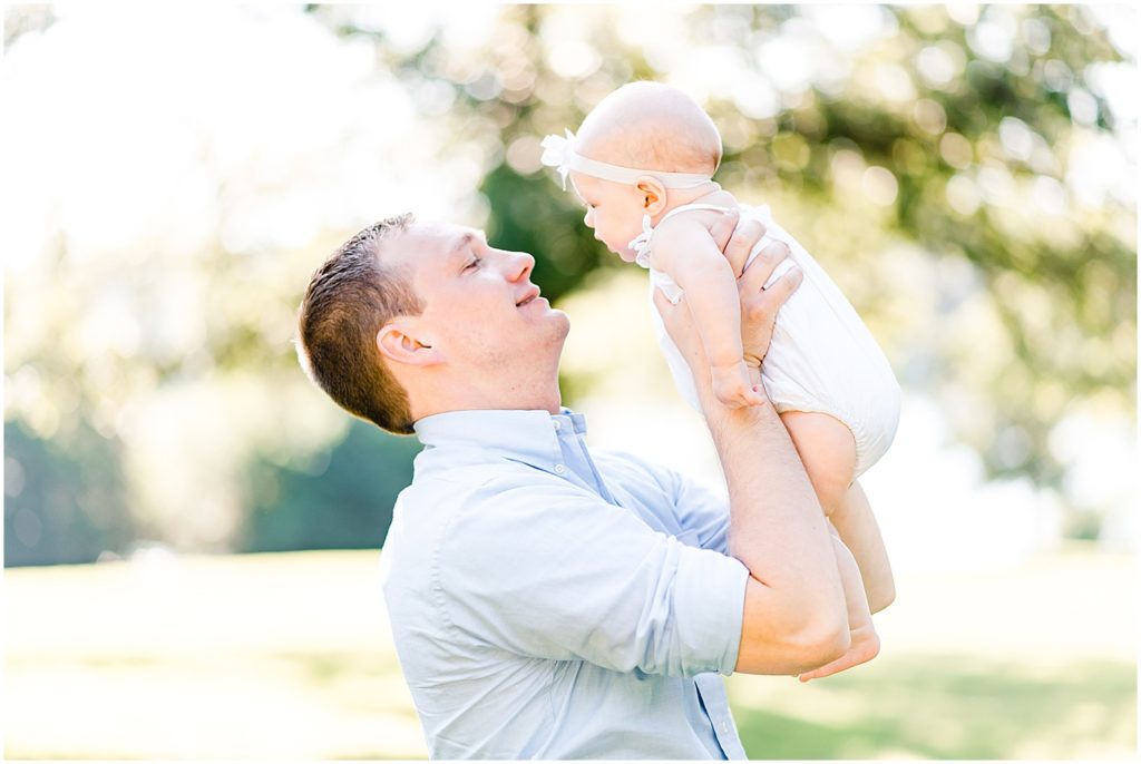young father holding baby girl up to face family portrait session