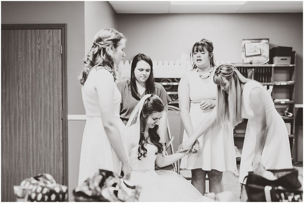 bridesmaids praying over bride black and white