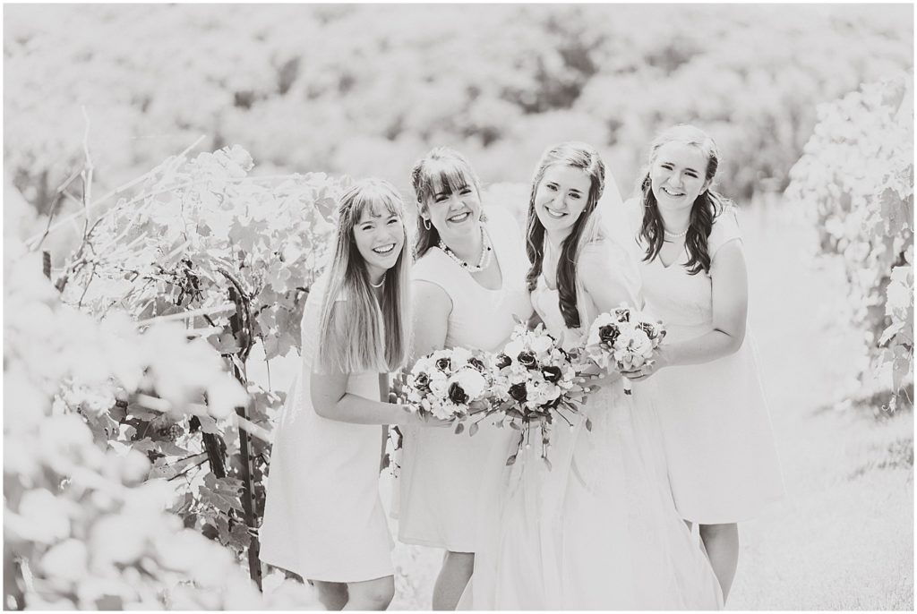 bridesmaids smiling at camera in vineyards black and white