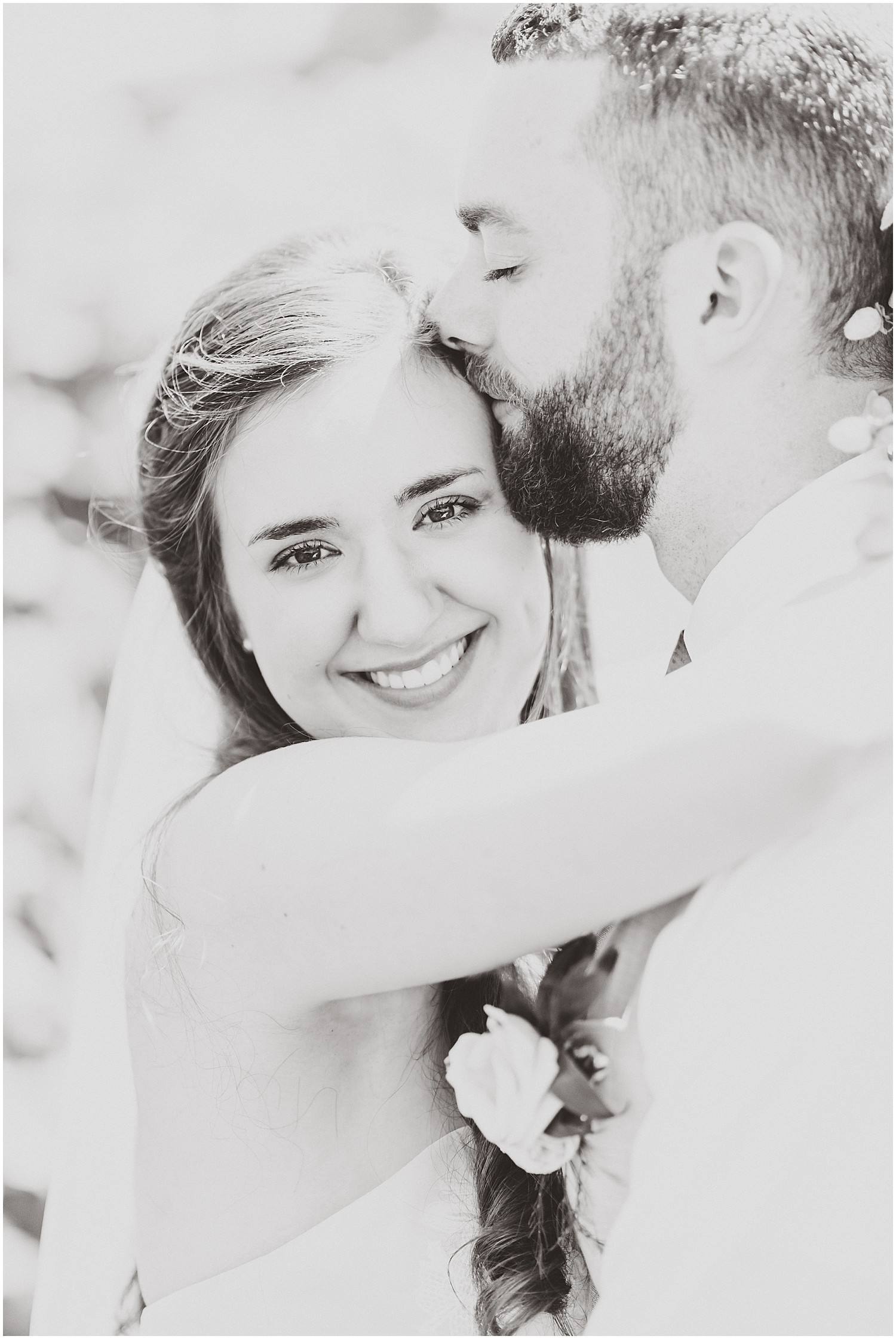 black and white close up of brides face husband kissing forehead