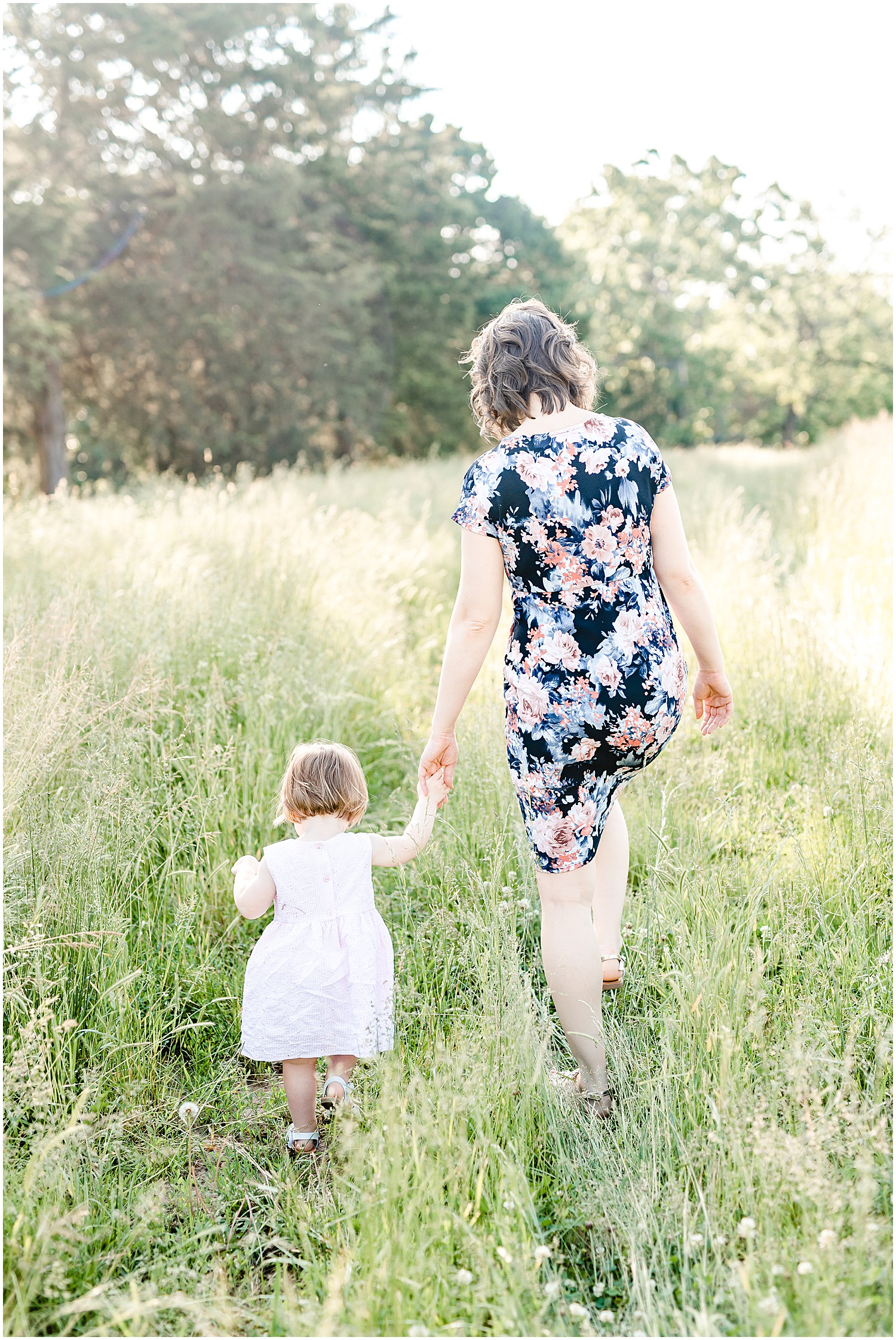 mom and young daughter walking through tall grass Westphalia mo family portrait session