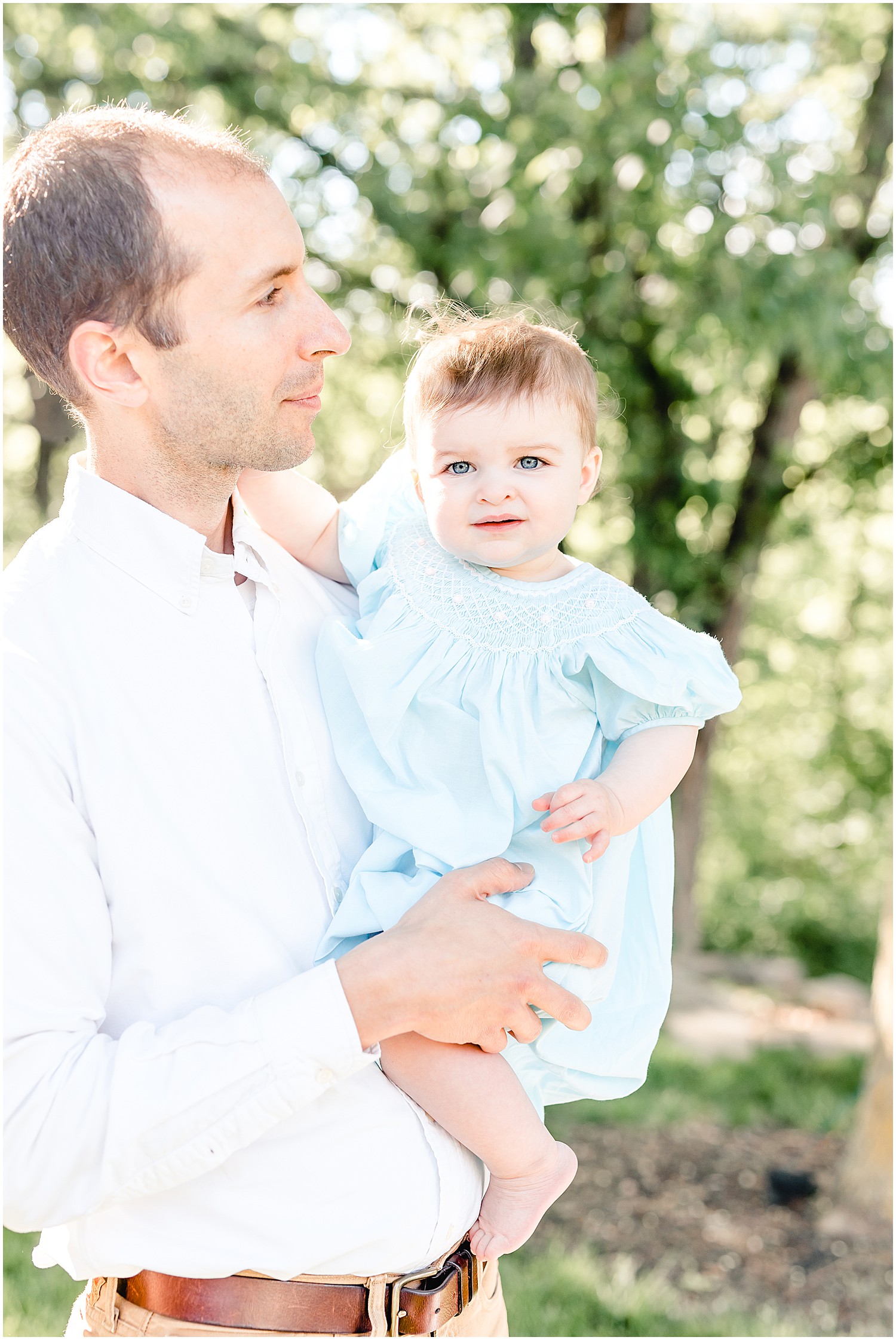 dad holding baby daughter under trees family portrait session