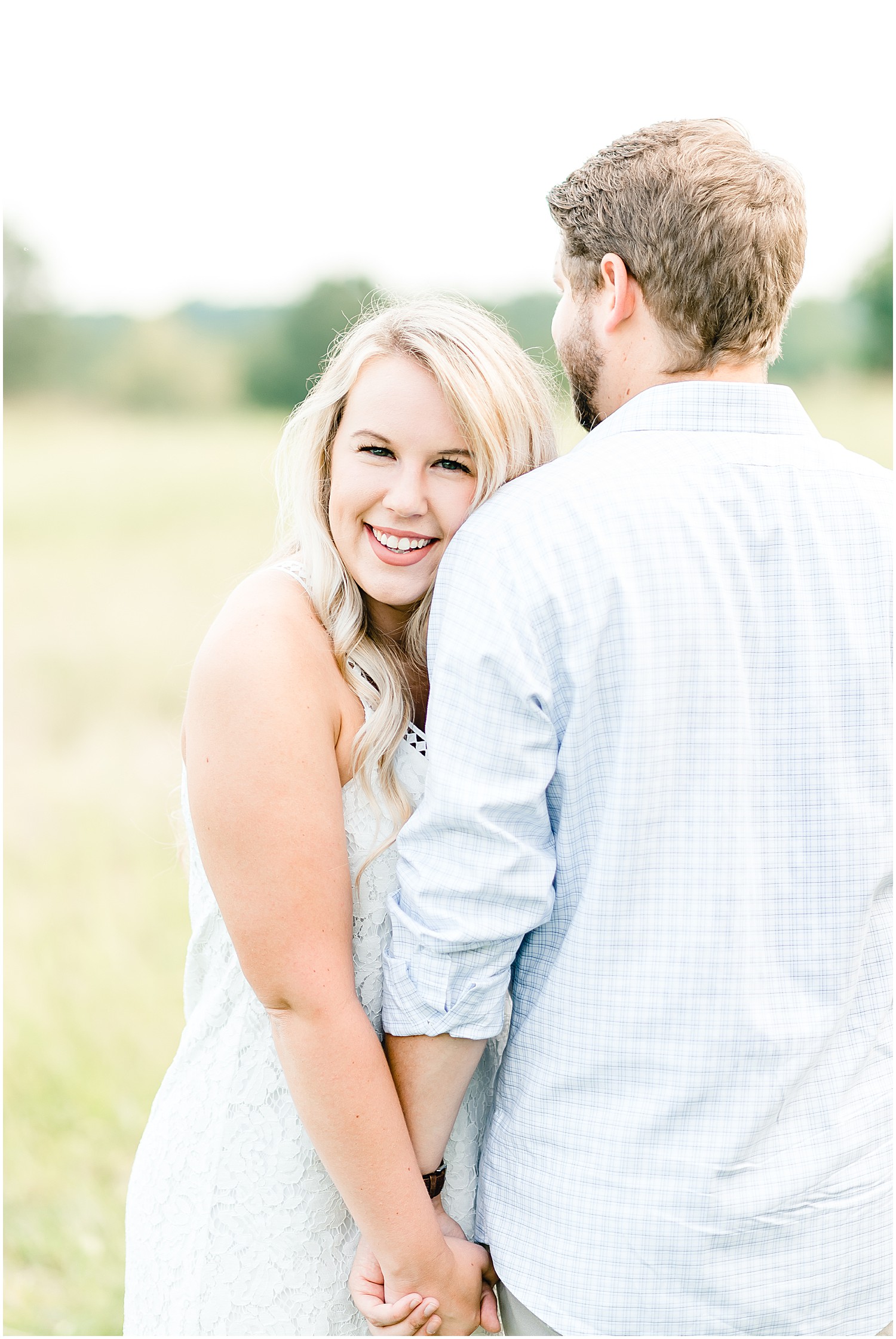Cooper's ridge engagement session couple standing in field of grass cuddling