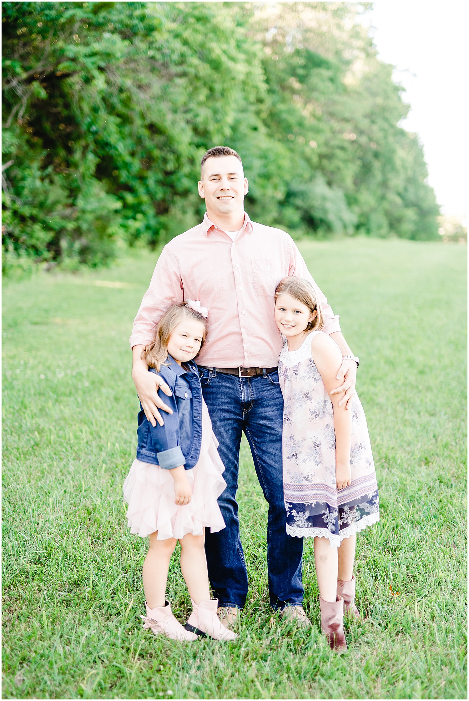 dad posing with daughters in grass