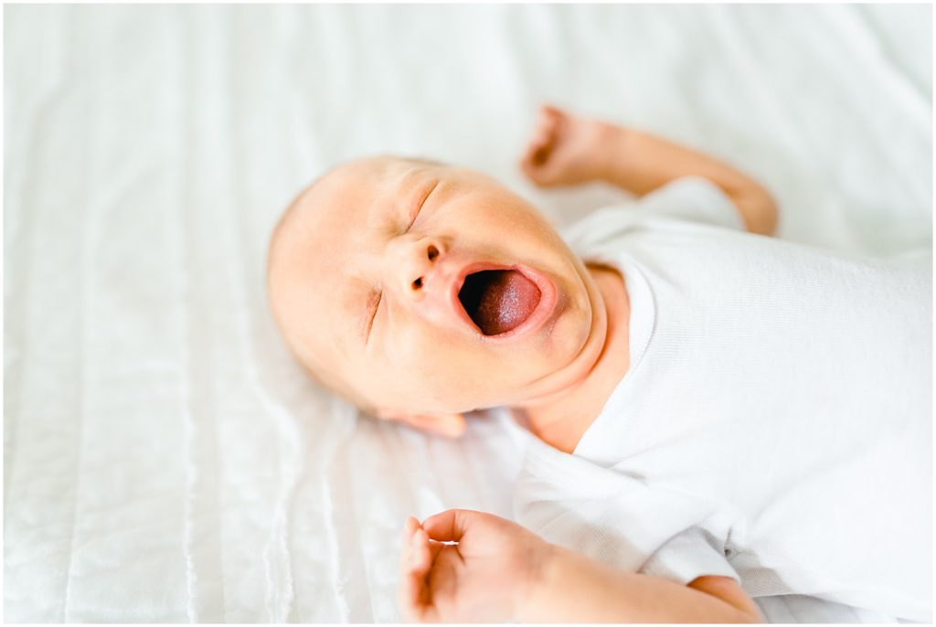 newborn baby yawning on white bed