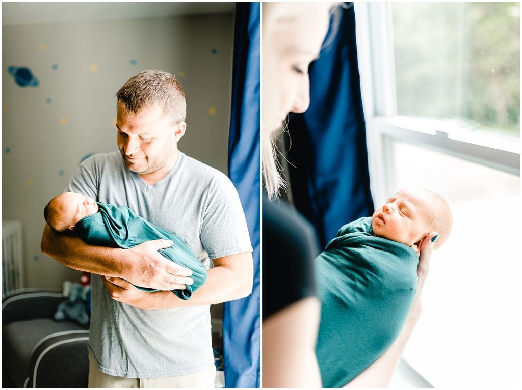 mom and dad holding newborn baby by window