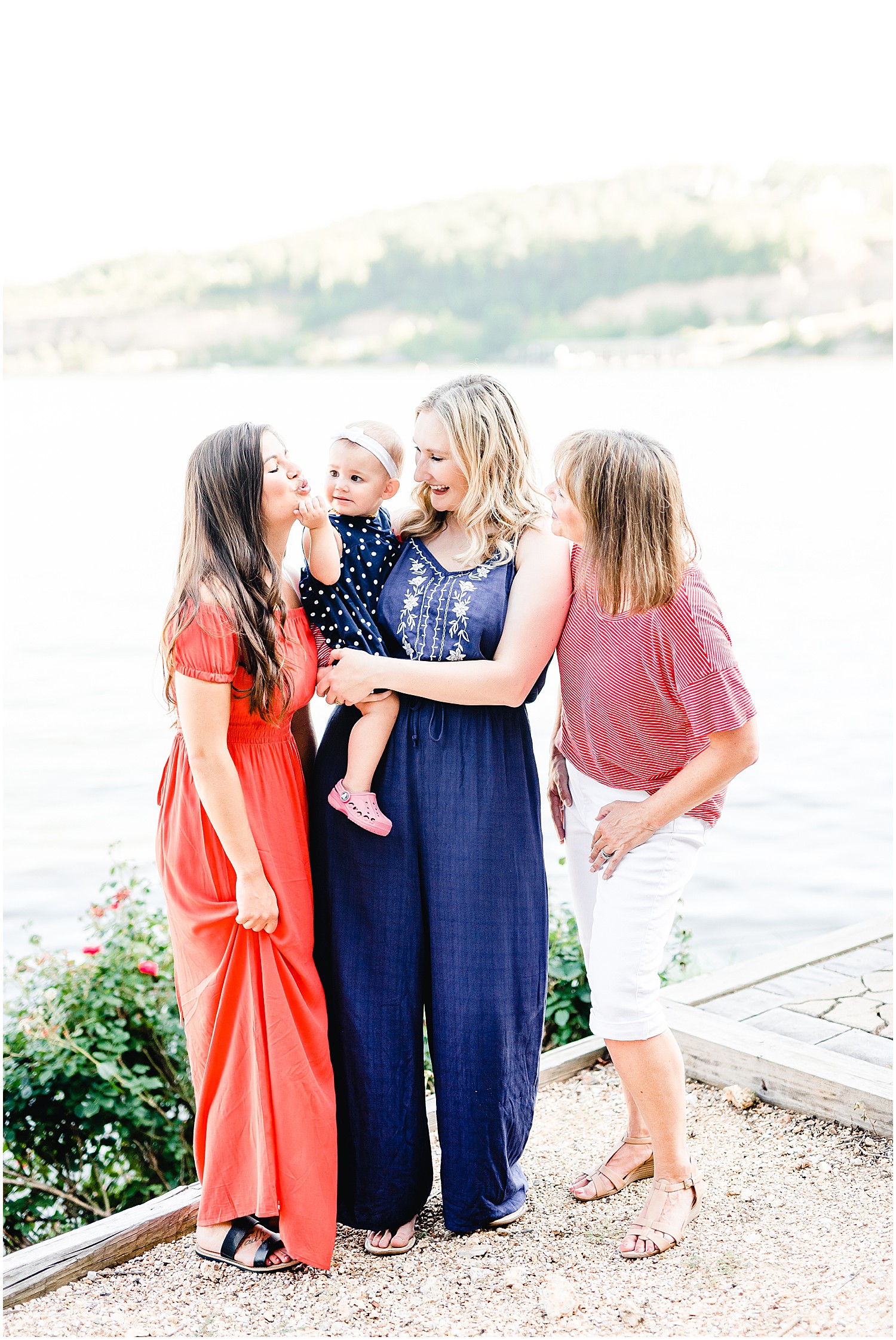women in family holding baby in front of lake of the ozark