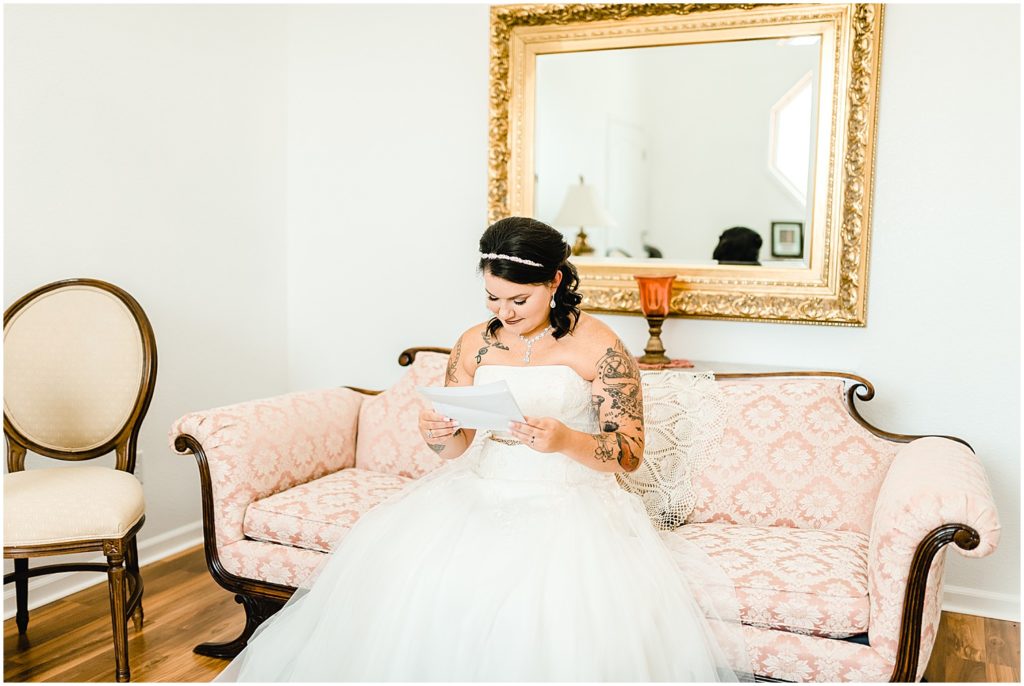 bride reading letter on getting ready room couch legacy barn