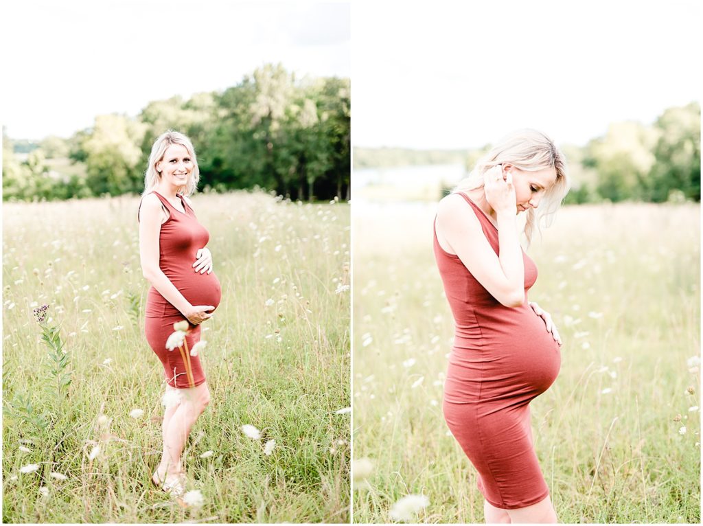 smiling pregnant mom in red short dress smiling at camera and looking at belly