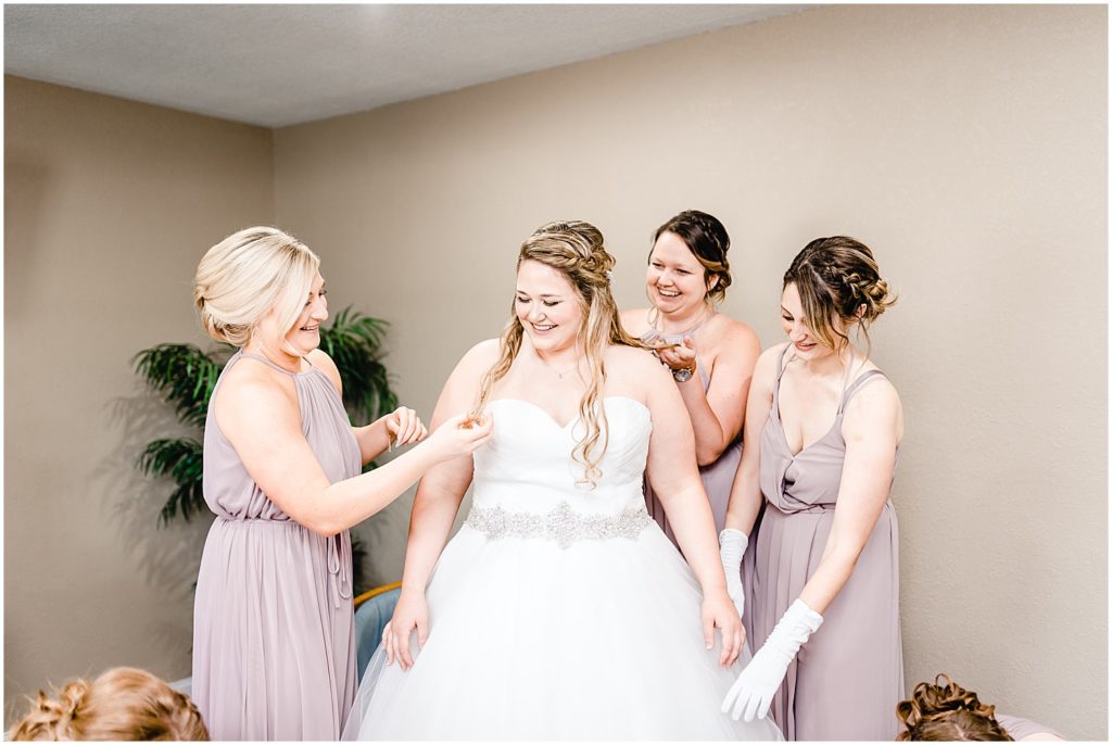 bridesmaids around bride in dress