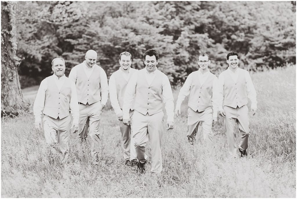 black and white groomsmen walking in field
