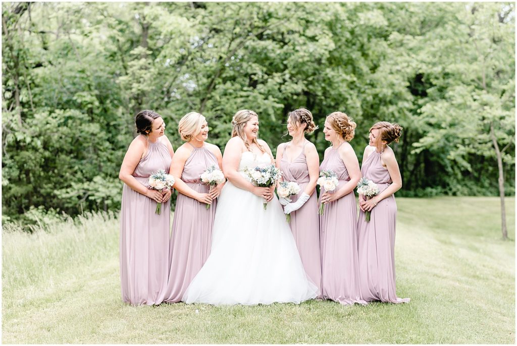 bridesmaids smiling at bride in grass