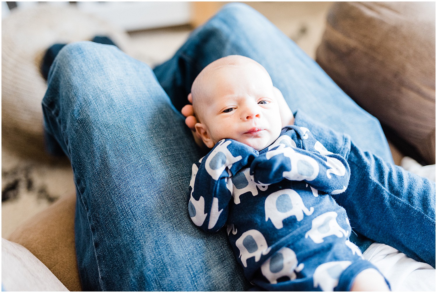 newborn baby boy laying in dads lap blue onesie