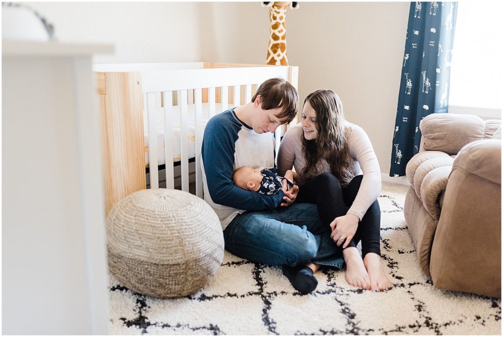 mom and dad with baby in nursery newborn session