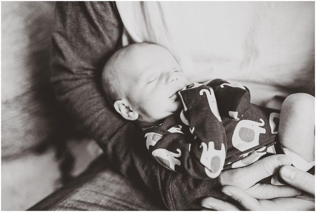black and white newborn boy sleeping in dad's arms