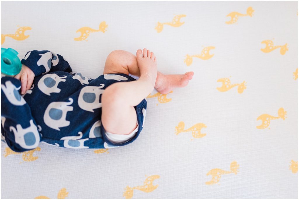 newborn feet in crib giraffe sheet