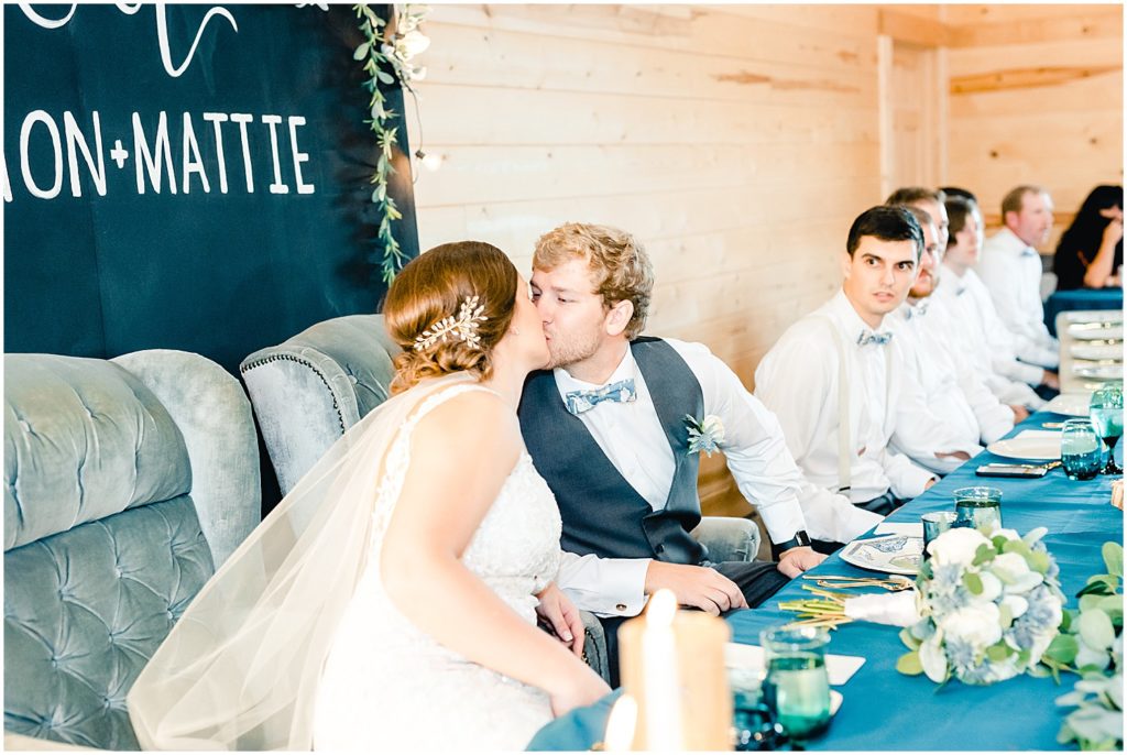 bride and groom kiss head table barn at honeysuckle farms