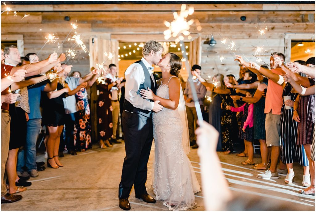bride and groom kissing barn at honeysuckle farms wedding sparklers patio reception
