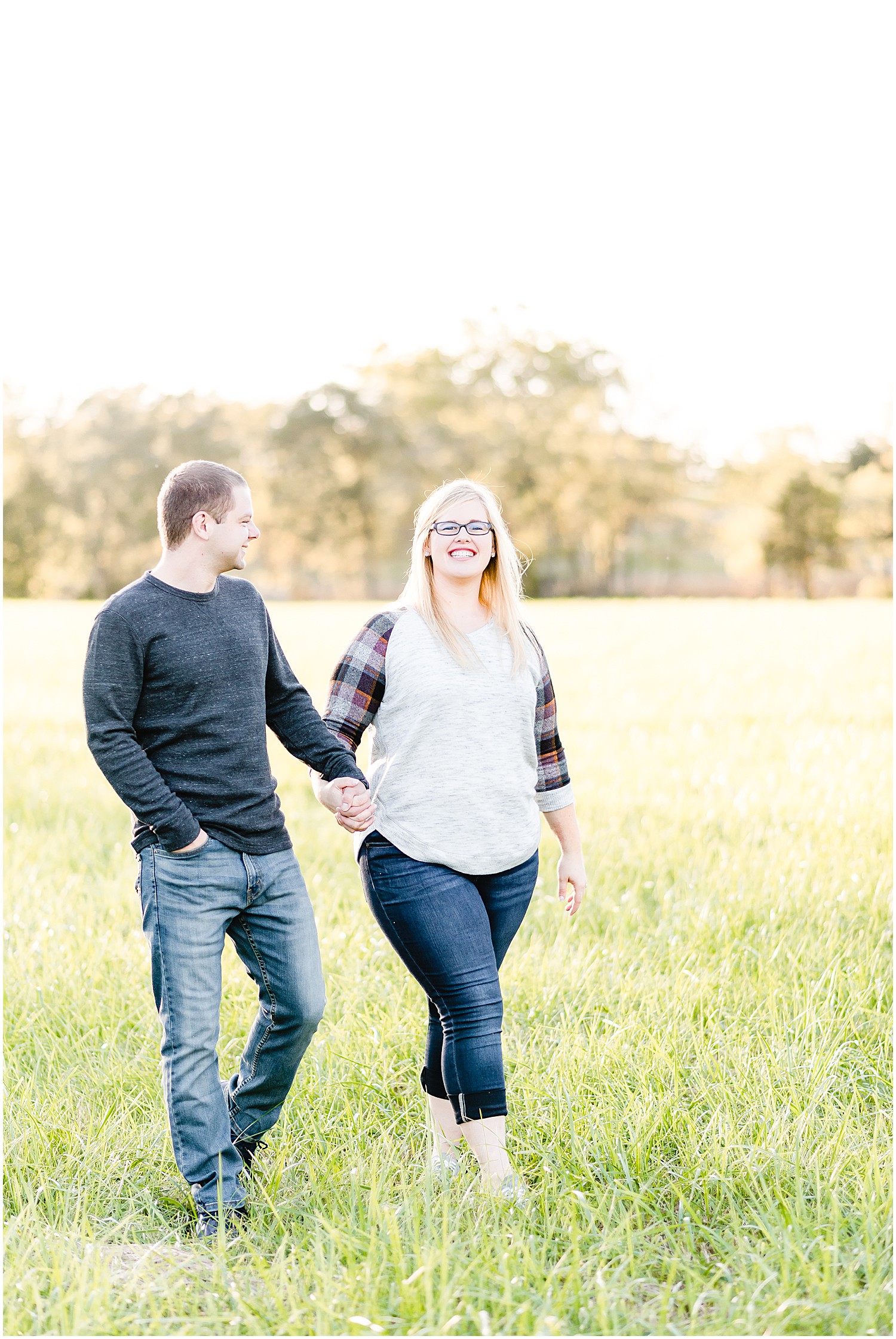 couple smiling walking through field 