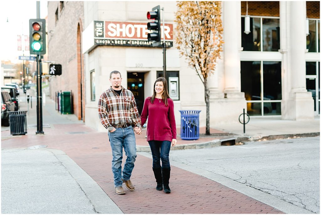 couple smiling at camera walking on street downtown columbia, mo engagement session