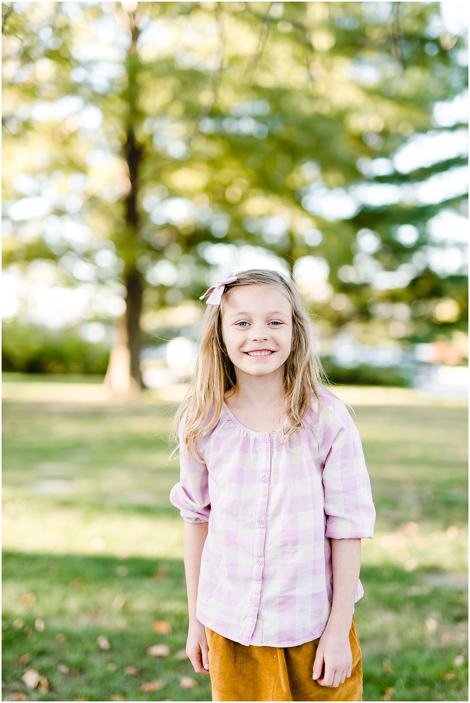 young blonde girl smiling at camera trees green