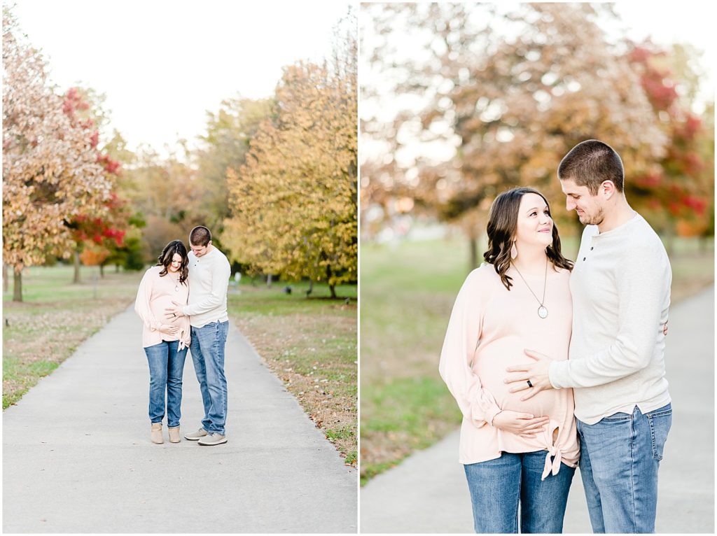 couple holding baby belly in park casual clothes