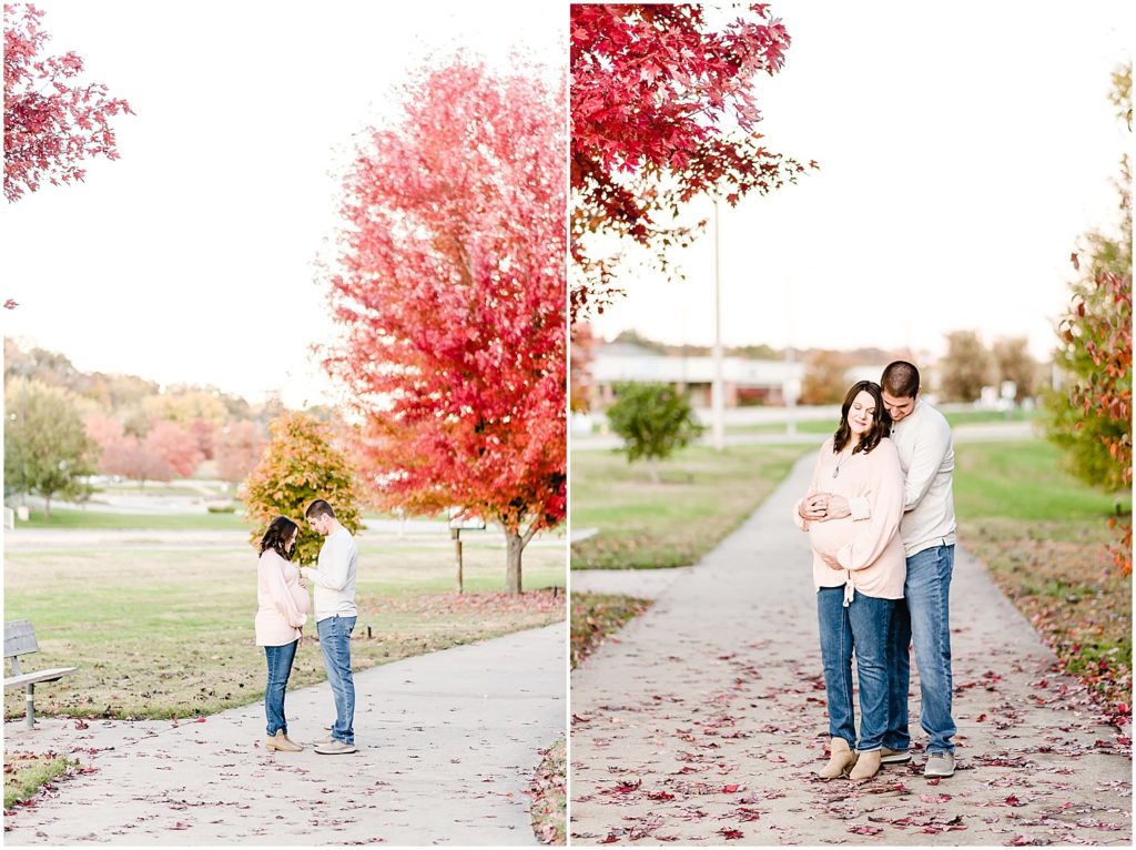expecting couple under fall trees holding baby belly