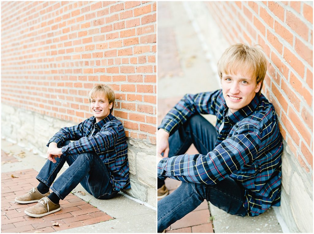 senior boy leaning against red brick wall