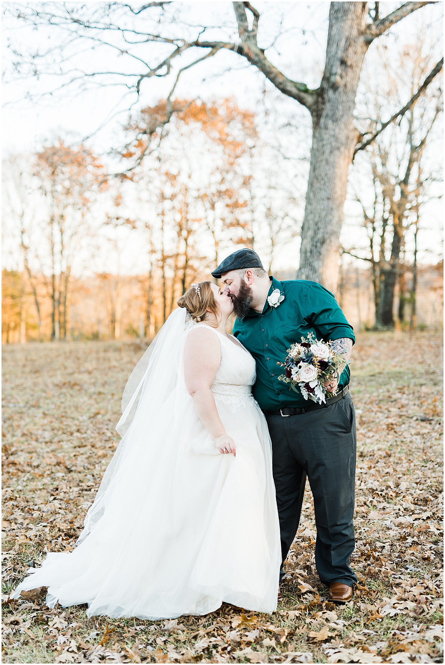 bride and groom kissing in field under tree weathered wisdom barn wedding