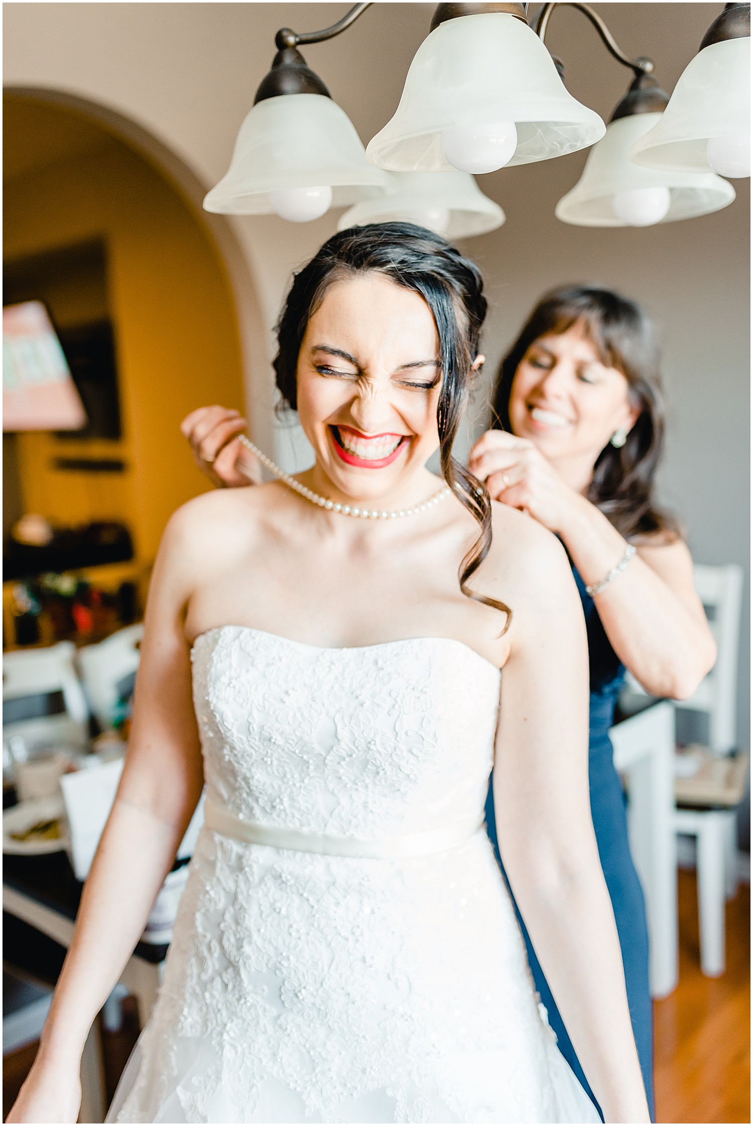 bride smiling mom putting necklace on