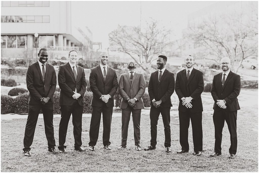 groom laughing with groomsmen black and white