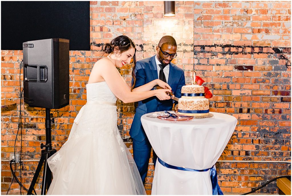 bride and groom cutting the cake brick wall behind