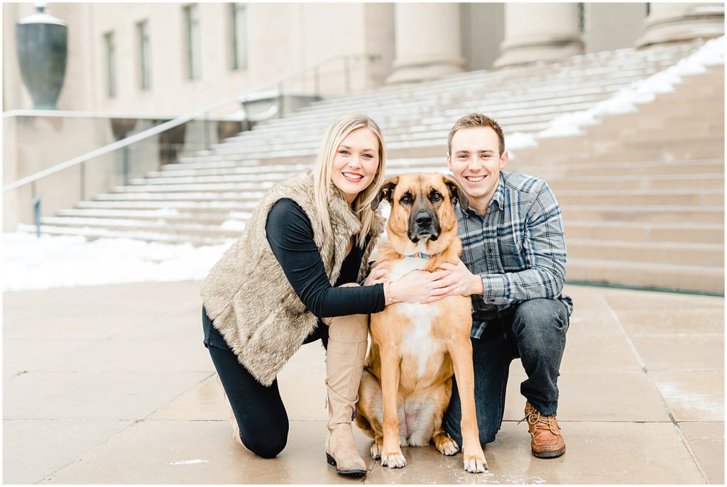 couple posing with dog outside art museum winter engagement session