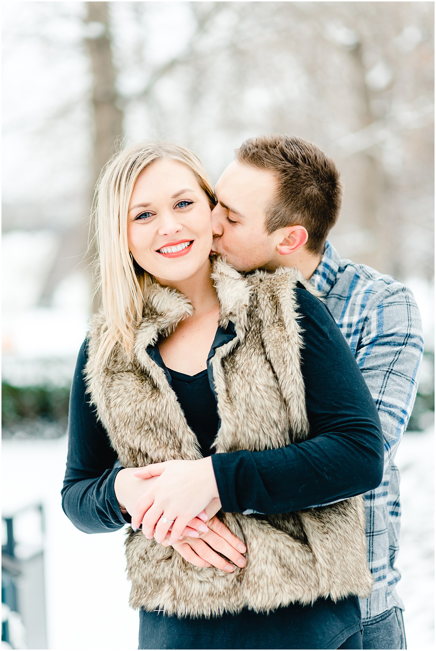 couple kissing on snow covered sidewalk winter engagement session