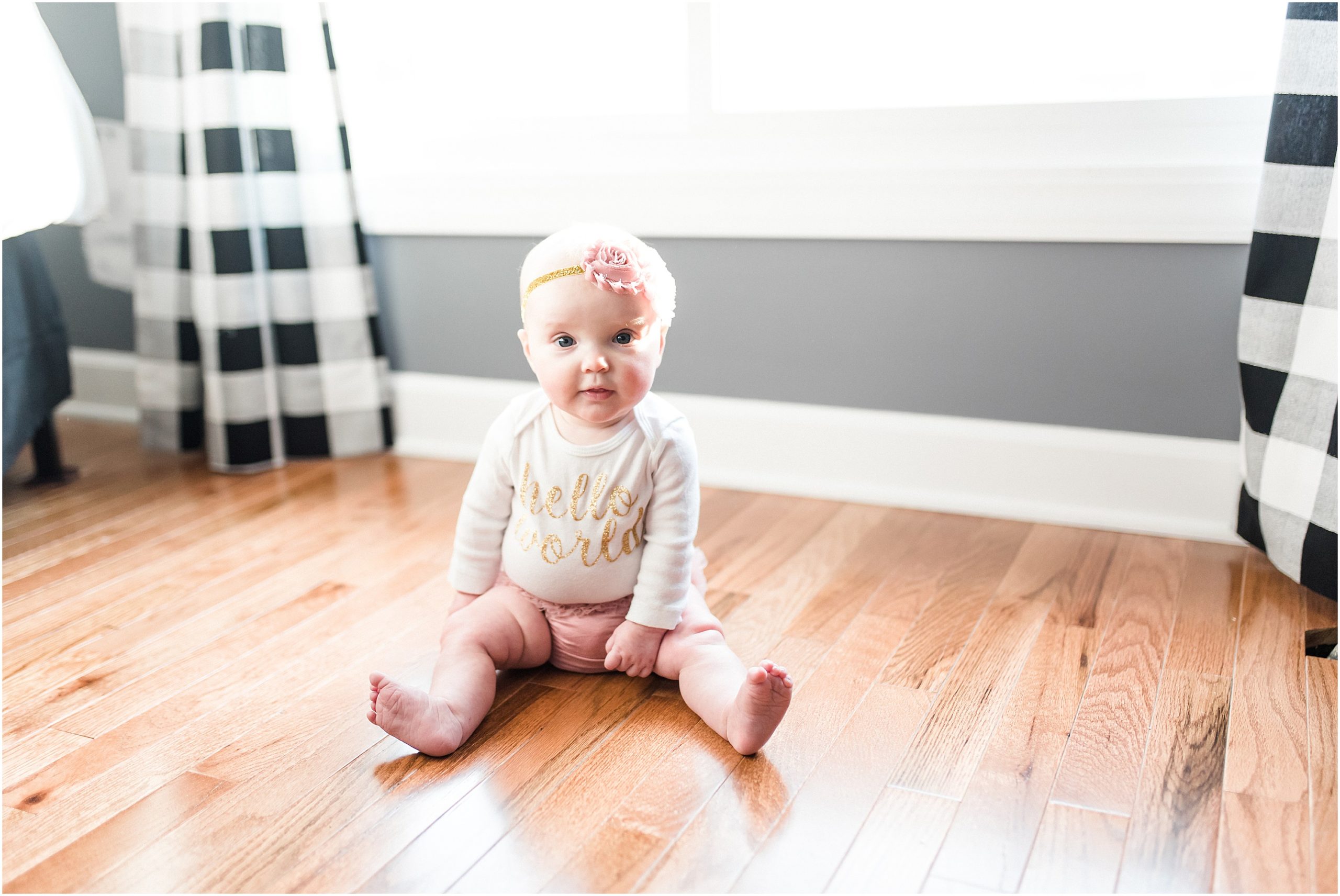 6 month old girl sitting on hardwood floors in her home