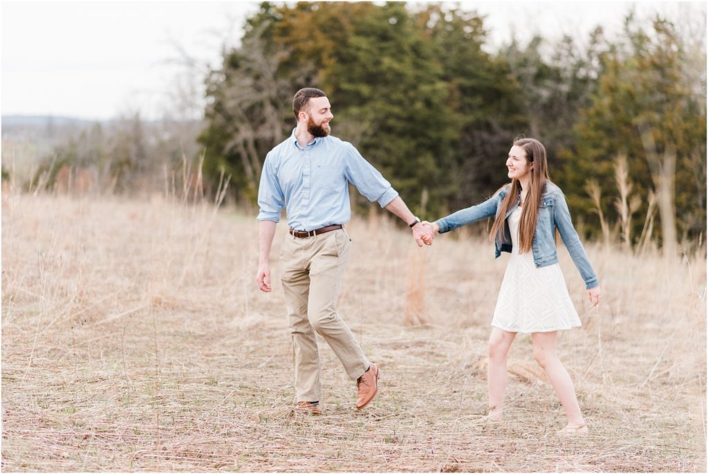 engaged couple poses in field at range nature center in jefferson city mo for engagement session