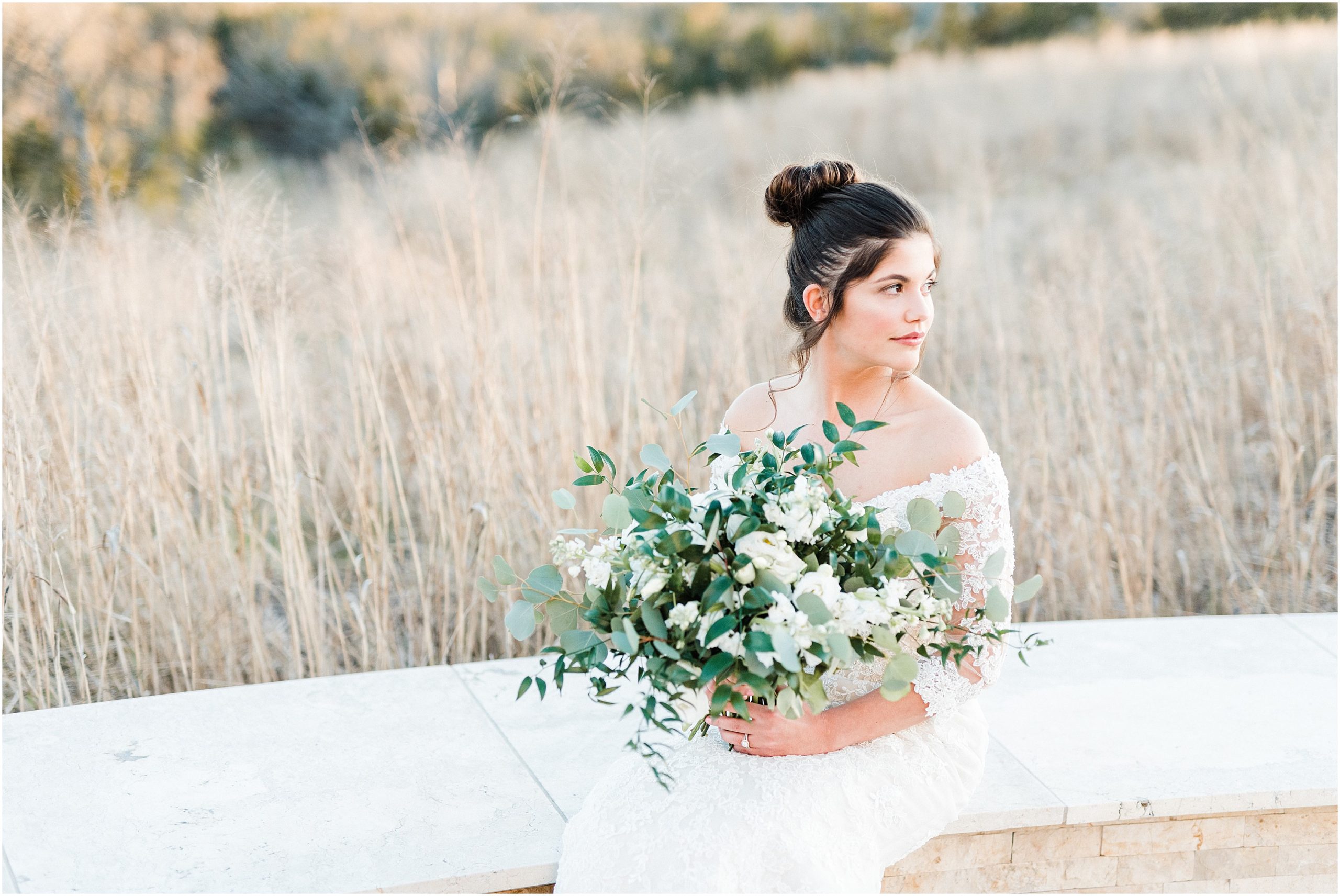 bride sitting on white bench with green and white bouquet