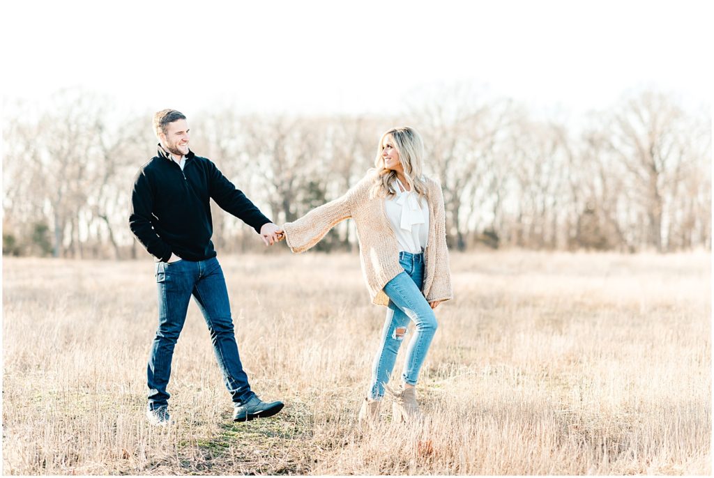 engaged couple walking in grass