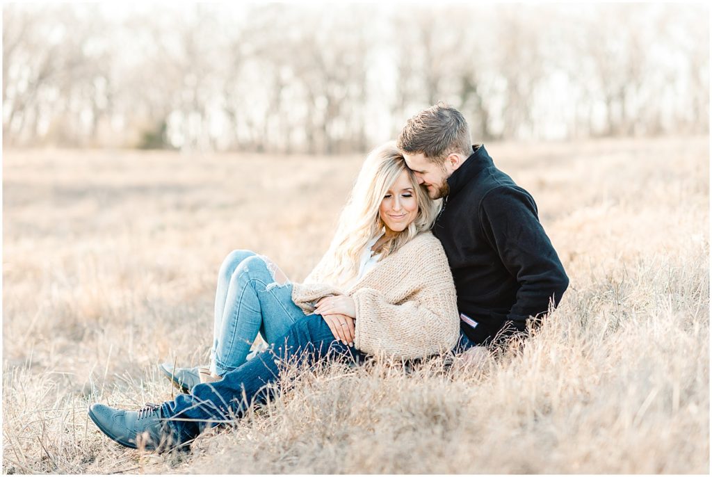 couple sitting snuggling in grass field