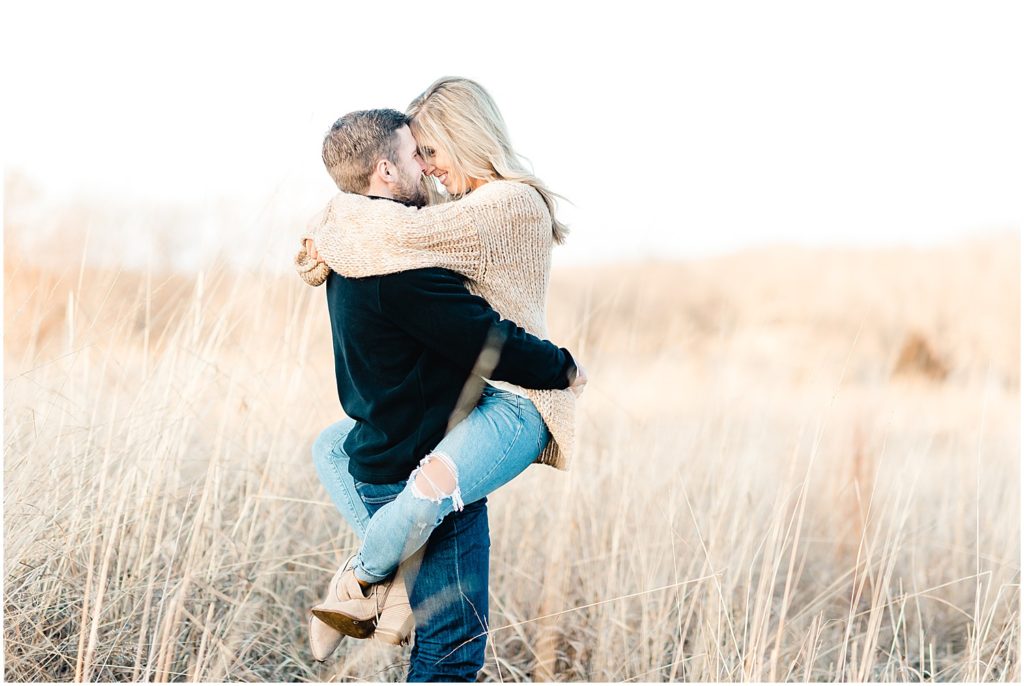 engaged couple holding each other in tall grasses