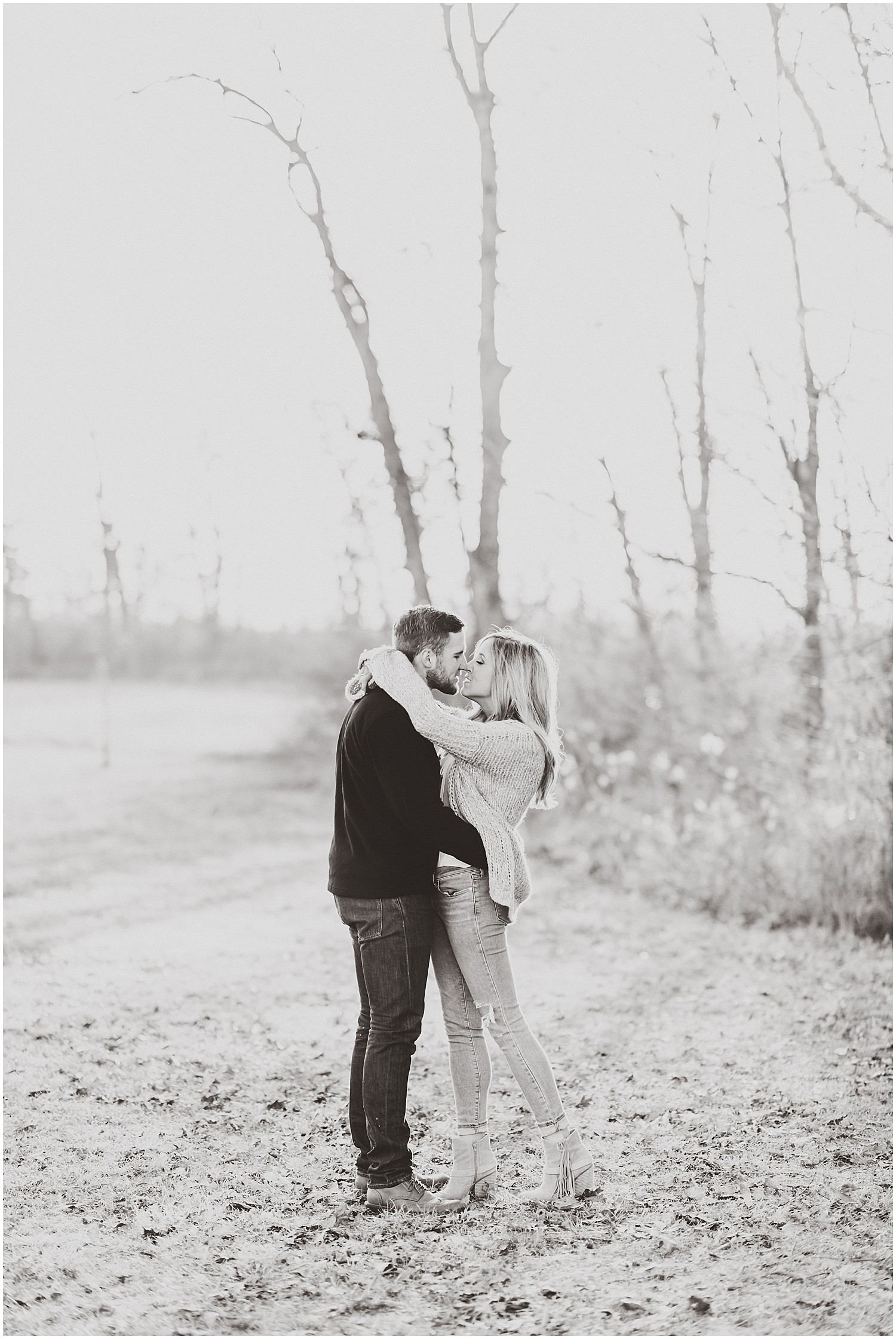 black and white of engaged couple kissing in sunlight