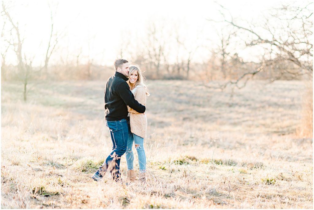 couple hugging laughing in grassy field golden sunlight