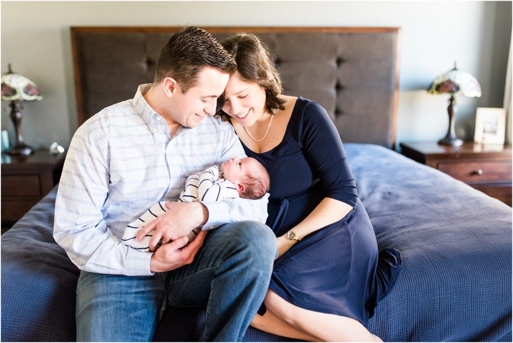 married couple holding newborn baby on bed for lifestyle newborn session in their home