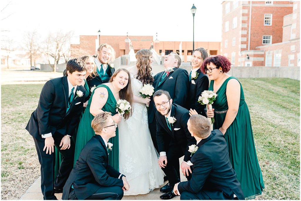bride and groom surrounded by wedding party laughing